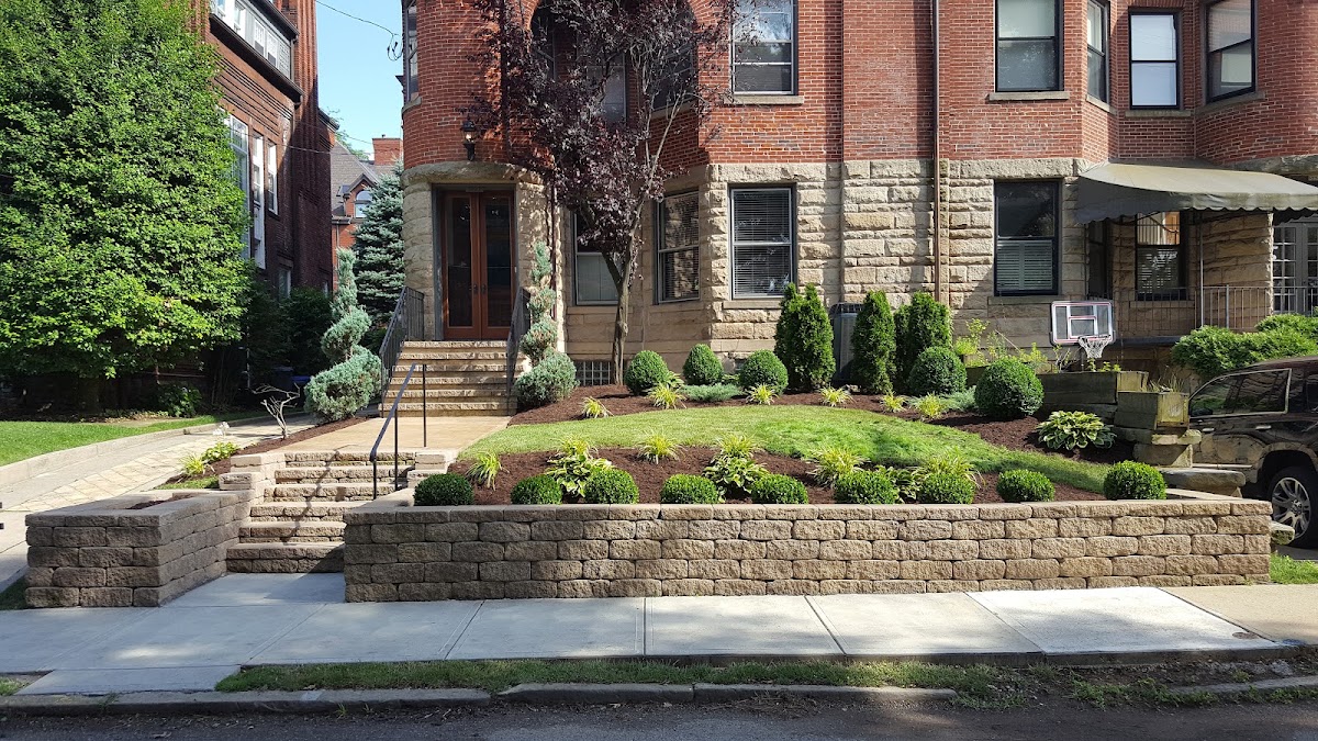 Terraced segmental block retaining wall and landscaping in front of a stately stone Pittsburgh rowhouse